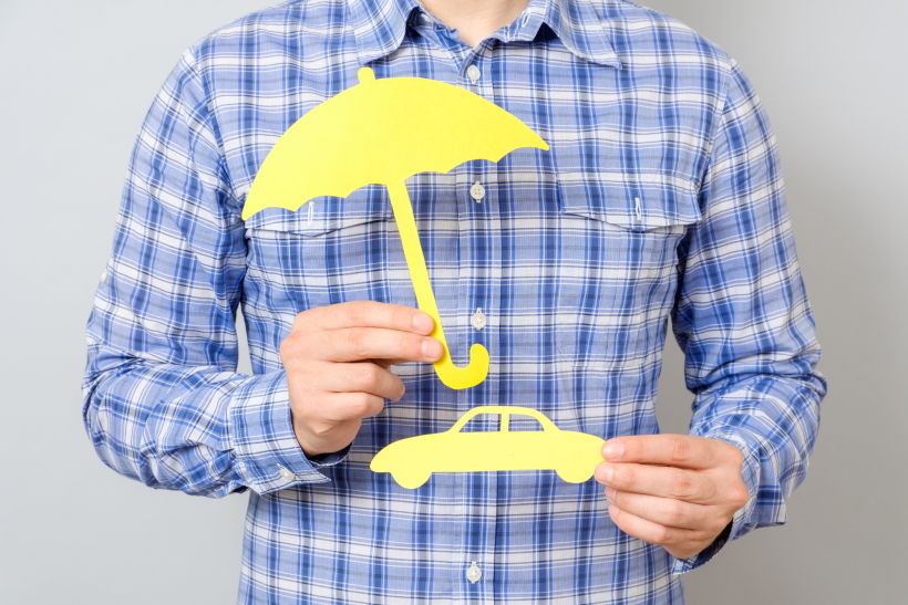 Man holding model of car and yellow umbrella concept for car insurance.