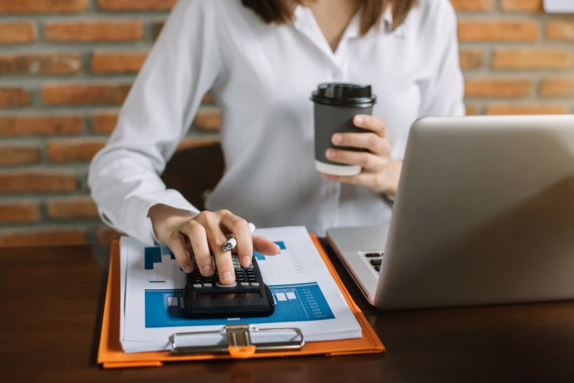 Female working on desk office with using a calculator to calculate taxes.