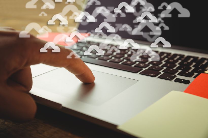 Close-up of laptop with upload icons.