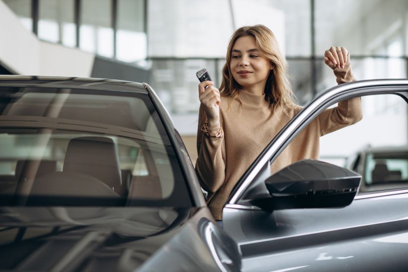 Woman holding keys by her new car.