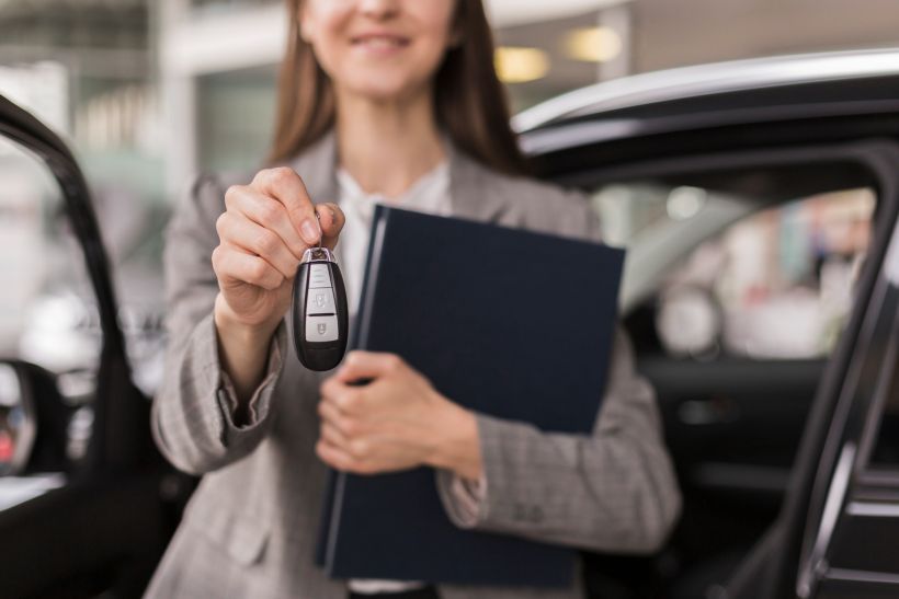 Female hands holding a folder and car keys.