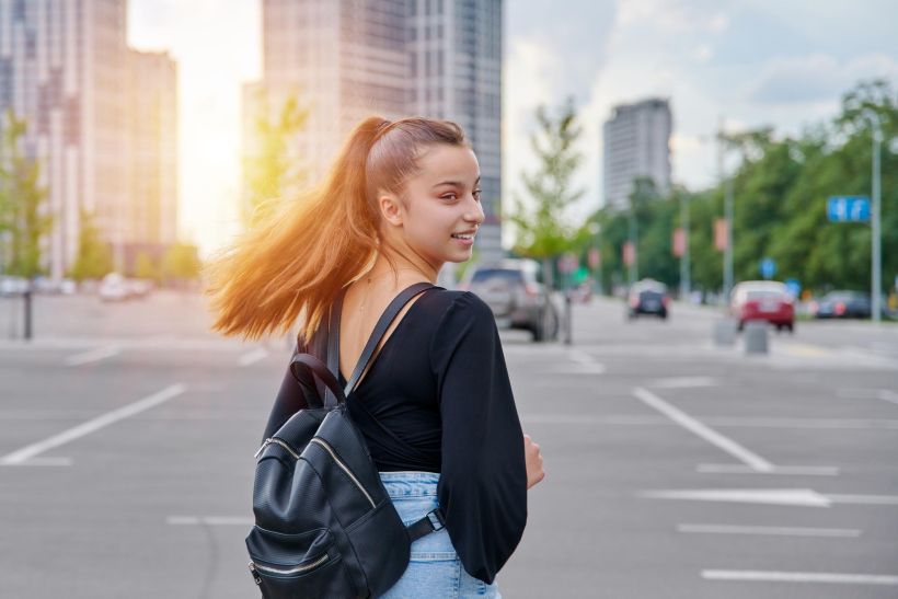 Fashionable beautiful smiling teenage girl in shorts with backpack.