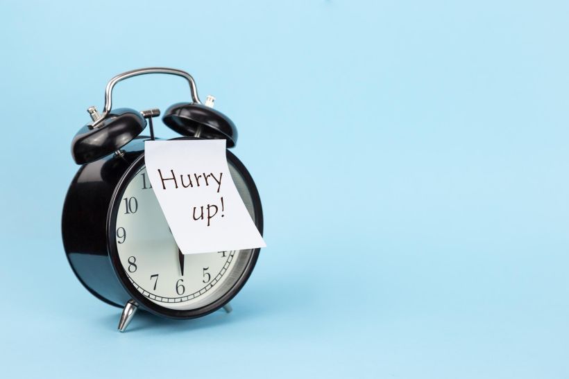 Close-up of alarm clock with paper against blue background.