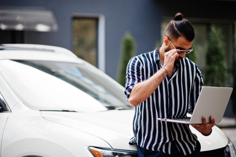 Successful man wear in striped shirt and sunglasses looking at his laptop with fine message.