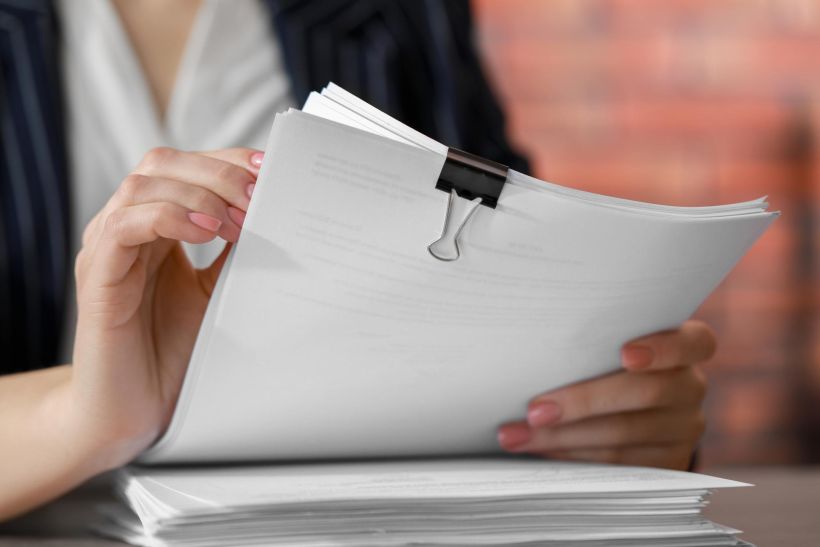 Woman arranging documents at a desk in an office, close-up.