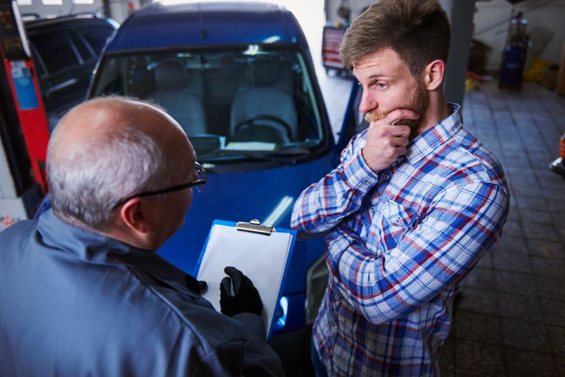 A customer is talking to a mechanic in a car repair shop.