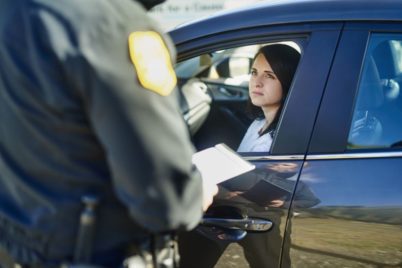Riding woman and traffic officer with ticket for checkpoint security.