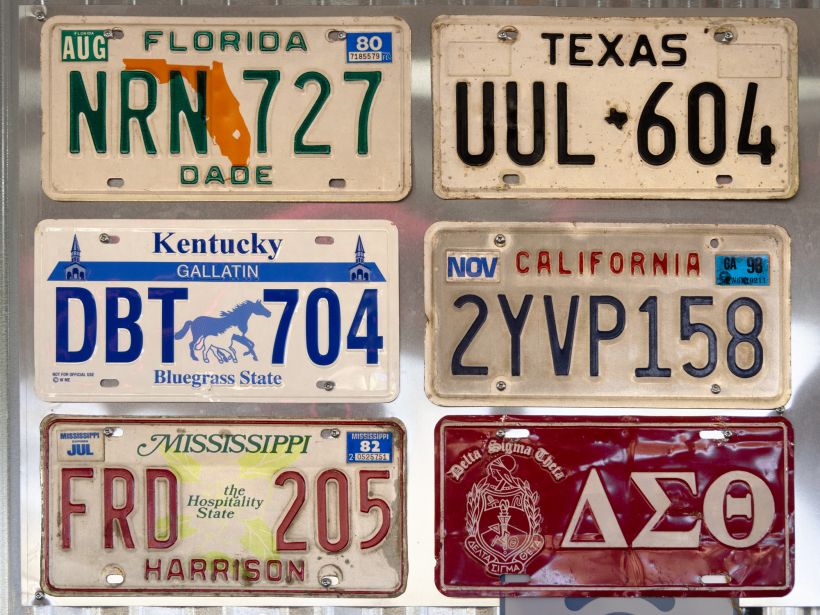 A collection of car license plates from different states and pin up style pictures in a biker cafe.