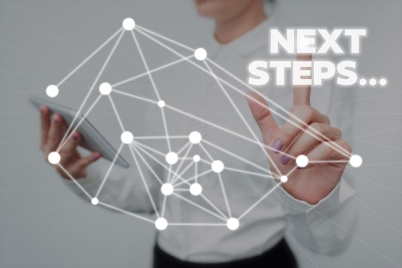 Low angle view of man using mobile phone with words “Next Steps”.