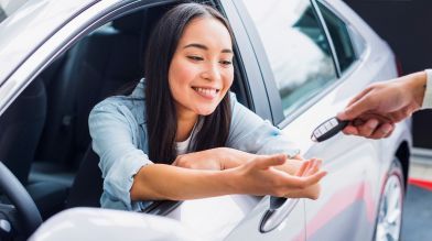 A smiling woman gets her car keys after figuring out how to transfer a car title in California