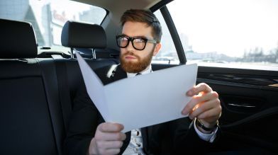 A man sitting in his vehicle reads over a finalized lien release on car title