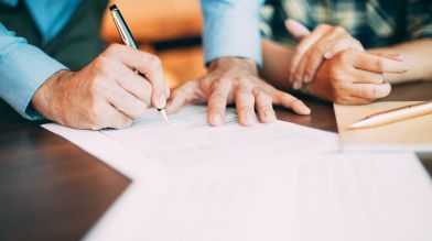 Two people sign the required documents to remove name from car title California